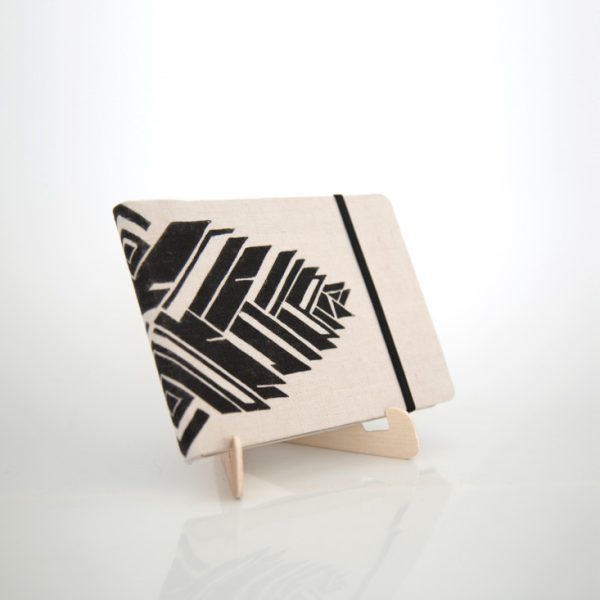 Libreta forrada en lino con estampado negro, elástico negro sobre una base de madera de la marca Leaftones creada por Diana Herrera Design
