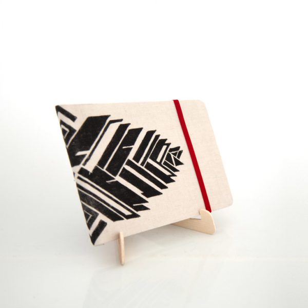 Libreta forrada en lino con estampado rojo, sobre una base de madera de la marca Leaftones creada por Diana Herrera Design