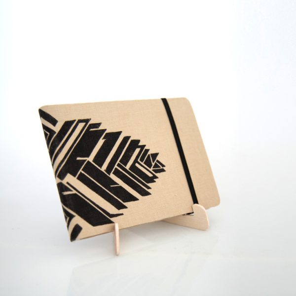 Libreta forrada en lino tono miel con estampado negro, sobre una base de madera de la marca Leaftones creada por Diana Herrera Design
