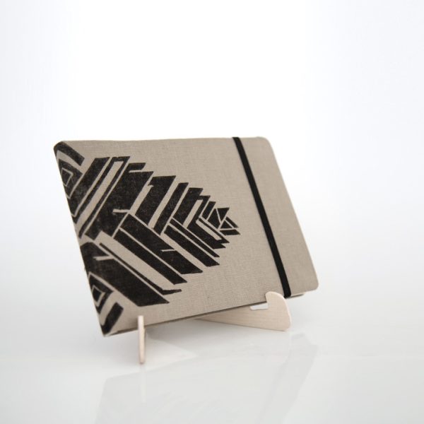 Libreta forrada en lino tono moca con estampado negro, sobre una base de madera de la marca Leaftones creada por Diana Herrera Design