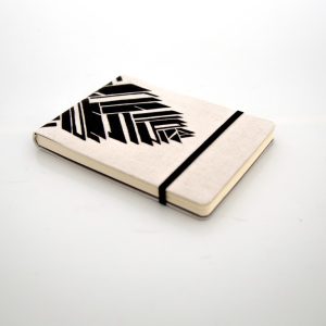 Libreta forrada en lino con estampado negro, elástico negro, cosida y encuadernada a mano sobre fonde grisáceo de la marca Leaftones creada por Diana Herrera Design