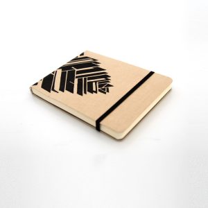 Libreta forrada en lino tono miel con estampado negro, elástico de cierre negro, cosida y encuadernada a mano sobre fonde grisáceo de la marca Leaftones creada por Diana Herrera Design