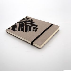 Libreta forrada en lino tono moca con estampado negro, elástico de cierre negro, cosida y encuadernada a mano sobre fonde grisáceo de la marca Leaftones creada por Diana Herrera Design