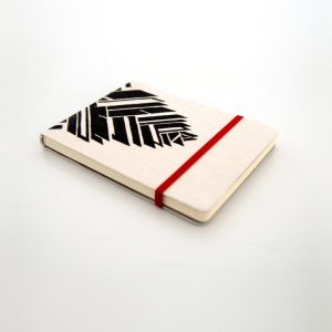 Libreta forrada en lino con estampado negro, cierre elástico rojo, cosida y encuadernada a mano sobre fonde grisáceo de la marca Leaftones creada por Diana Herrera Design