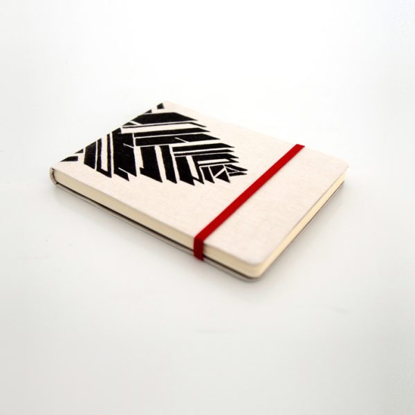 Libreta forrada en lino con estampado negro, cierre elástico rojo, cosida y encuadernada a mano sobre fonde grisáceo de la marca Leaftones creada por Diana Herrera Design