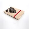 Libreta forrada en lino tono miel con estampado negro, elástico de cierre rojo, cosida y encuadernada a mano sobre fonde grisáceo de la marca Leaftones creada por Diana Herrera Design